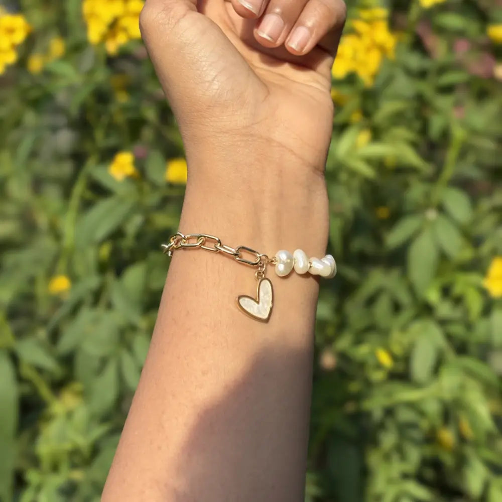 Hand wearing a bracelet with a heart charm